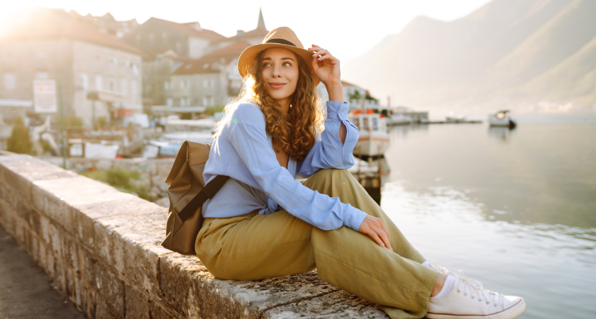 Mladá cestovatelka s kloboukem vzhlížející do dálky